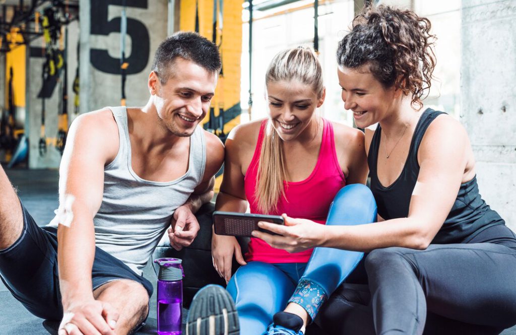 A personal trainer showing to her customers how an online booking system works on a phone. Source: Freepik